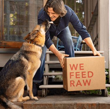 Man holding We Feed Raw box with dog