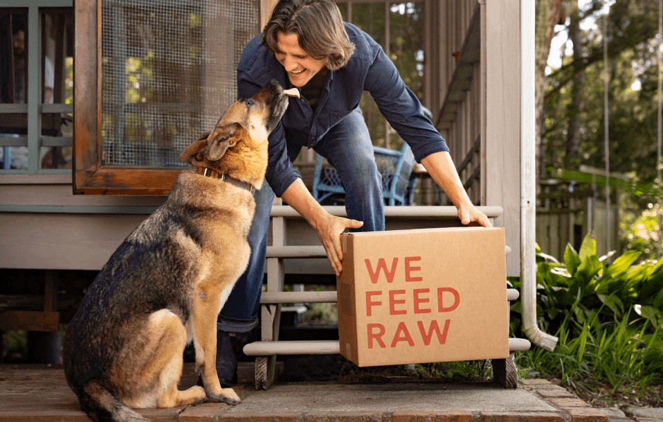 Man holding We Feed Raw box with dog